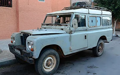 An old Land Rover parked in front of a building, showcasing its vintage design against the architectural backdrop.