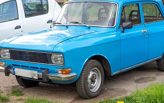 A blue car on the roadside illustrating the importance of Junk Car Removal Services in the area.