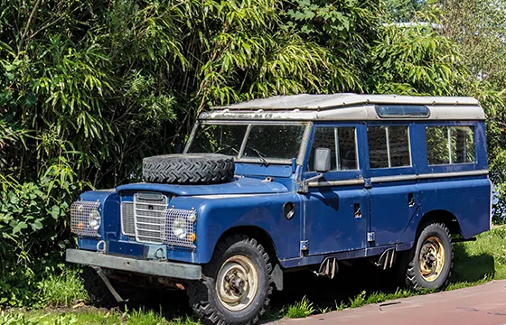 Land Rover Defender 90 parked in a driveway with a sign promoting cash for junk SUVs in Dacula GA.