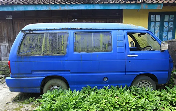 A blue van parked in front of a house promoting cash for junk cars in Dacula GA.