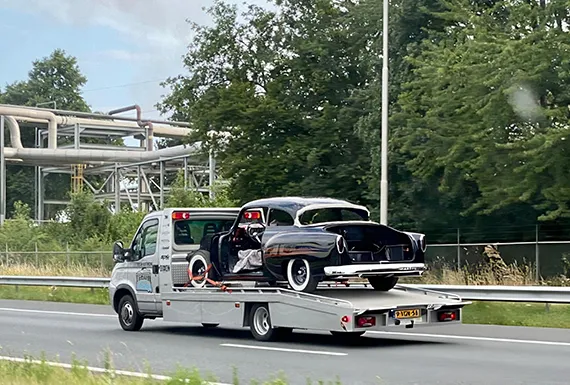 A flatbed truck towing a car, illustrating quick cash for junk vans.