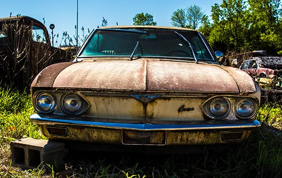 An old rusty car overgrown with grass, representing junk cars for cash in Duluth, GA.