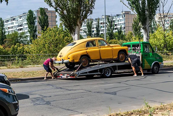 A man loads a car onto a flatbed truck, part of the junk car removal service in Grayson, GA.