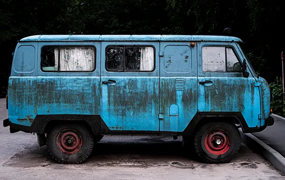 An old blue van in a parking lot, connected to powerful junk car solutions in Grayson, GA.