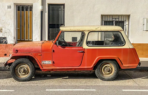 An old red jeep parked on the roadside for cash offers on junk SUVs.