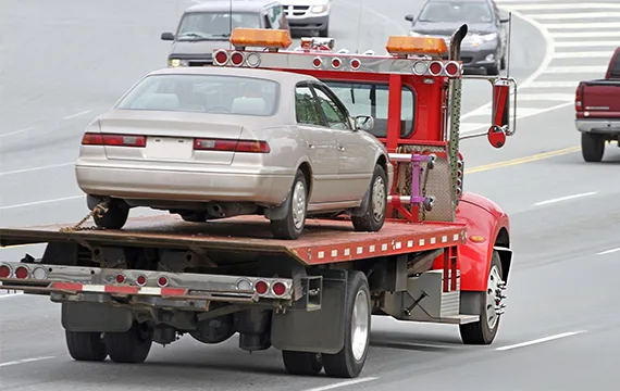 A flatbed truck towing a car for professional junk car removal services in Lawrenceville GA.