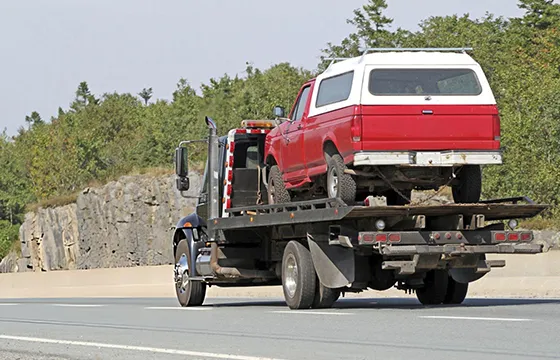 A red truck is being towed by a flatbed tow truck in a scene related to cash for junk SUVs in Loganville GA.