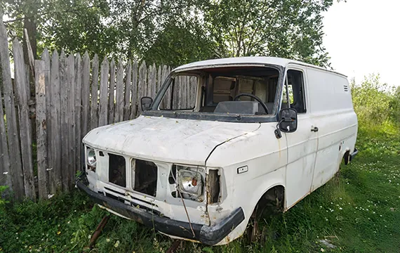 An old white van parked in the grass near Loganville GA for cash for junk vans service.