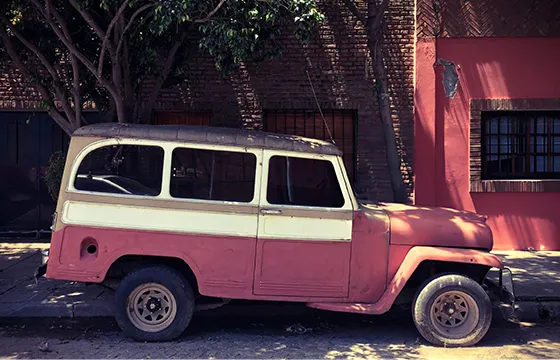 Old pink jeep parked in front of a building related to cash offers for junk trucks in Snellville GA.