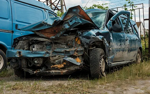 A damaged car parked beside a blue van, relevant to junk car buying services in Snellville, GA.