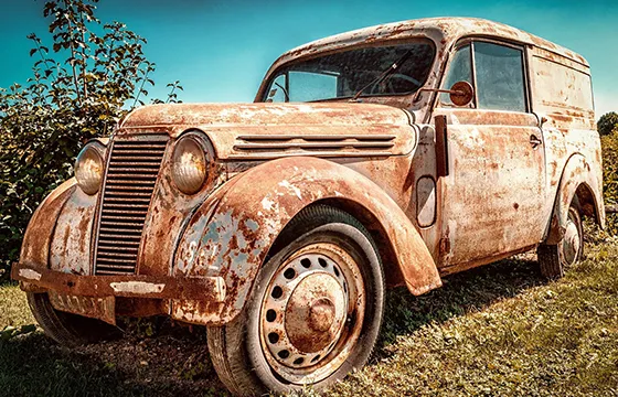 An old, rusty car overgrown with grass, related to the cash for junk cars service in Stone Mountain, GA.