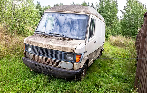 A weathered van situated in dense grass, connected to dependable cash offers for junk cars in Stone Mountain, GA.